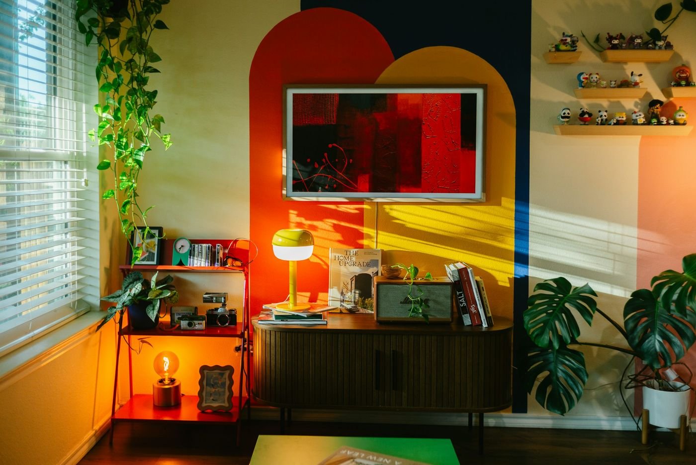 Colorful FunHaus-inspired interior with red accent chair, curved sofa, and sculptural lamp