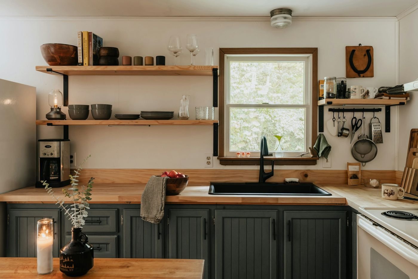 Stylish kitchen styled with natural wood open shelves, ceramic dishes, and warm neutral tones