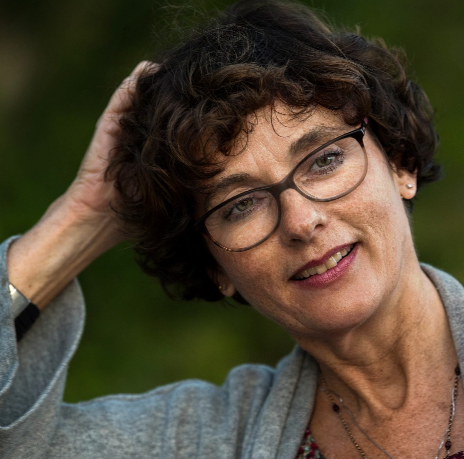 Mature woman over 50 with a short curly pixie cut and glasses