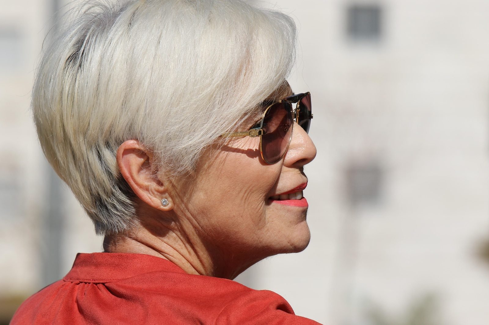 Mature woman with a short silver pixie cut wearing a red scarf