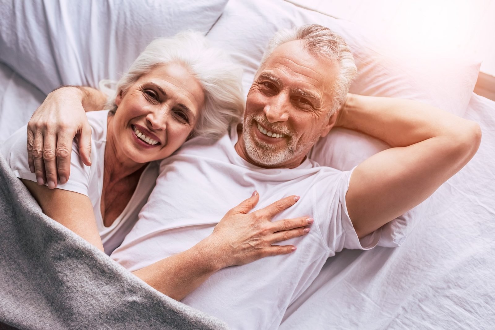 Senior couple smiling together in bed with white hair